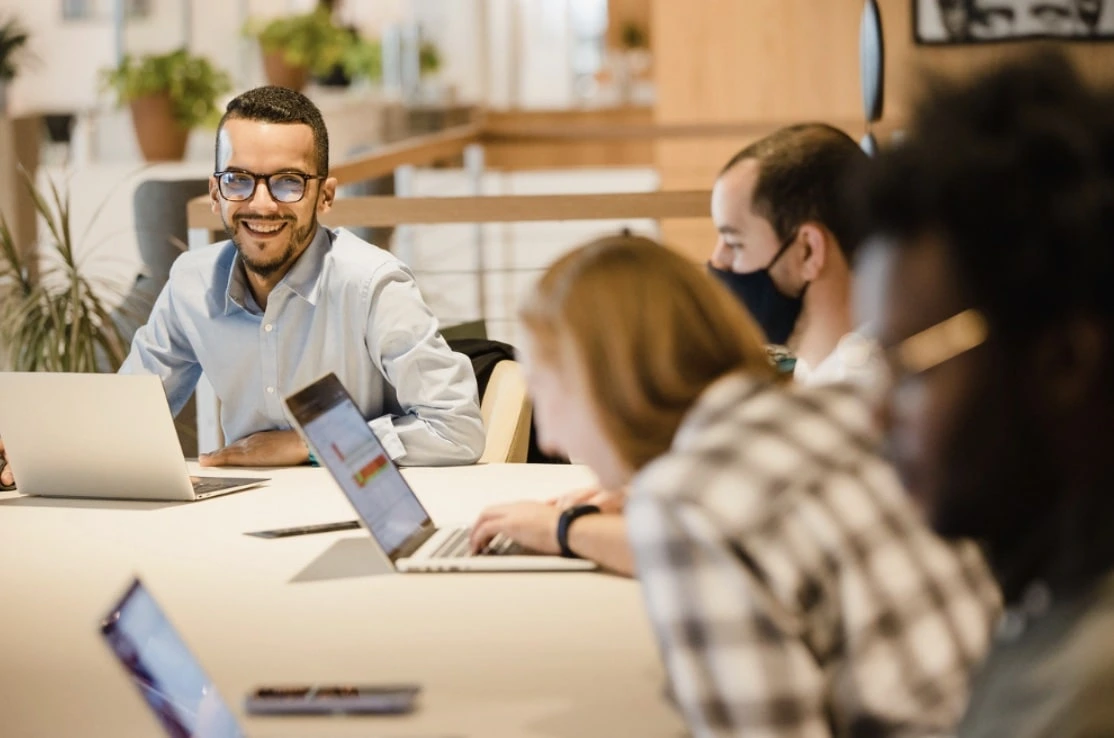 Photograph of Media Tradecraft team members laughing at a desk with laptops out.